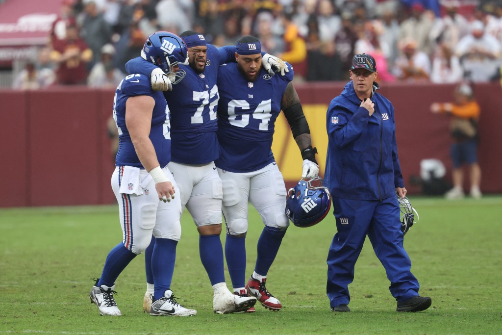 New York Giants offensive lineman Jermaine Eluemunor (72) is helped off the field after an injury during a game against the Washington Commanders.