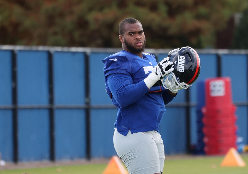New York Giants offensive tackle Evan Neal holds his helmet during practice.