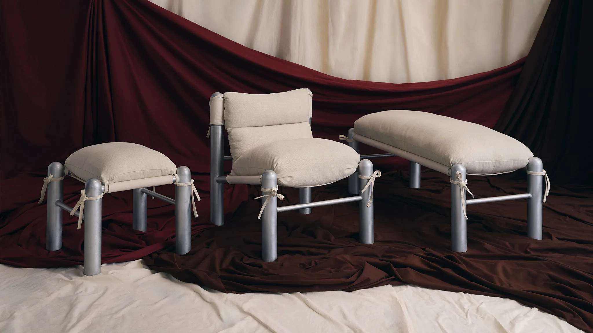 Three padded chairs with silver metal frames on draped fabric, nycxdesign manhattan furniture setting.