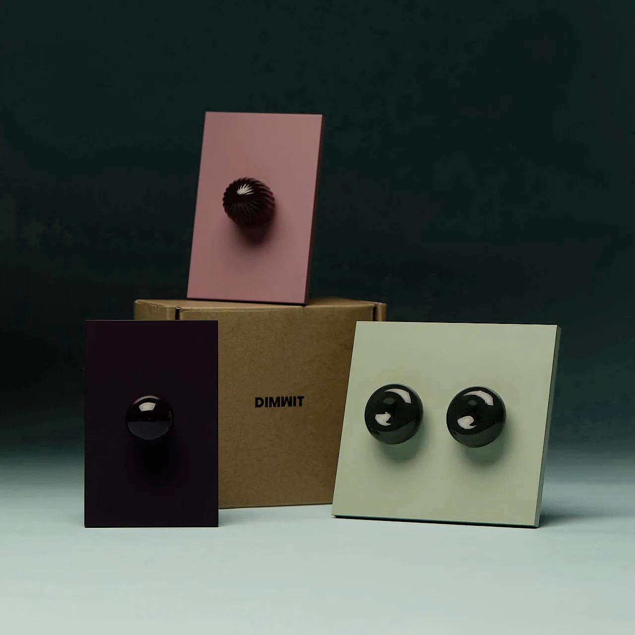 Three rectangular panels with knob-like objects in pink, beige, and dark brown.