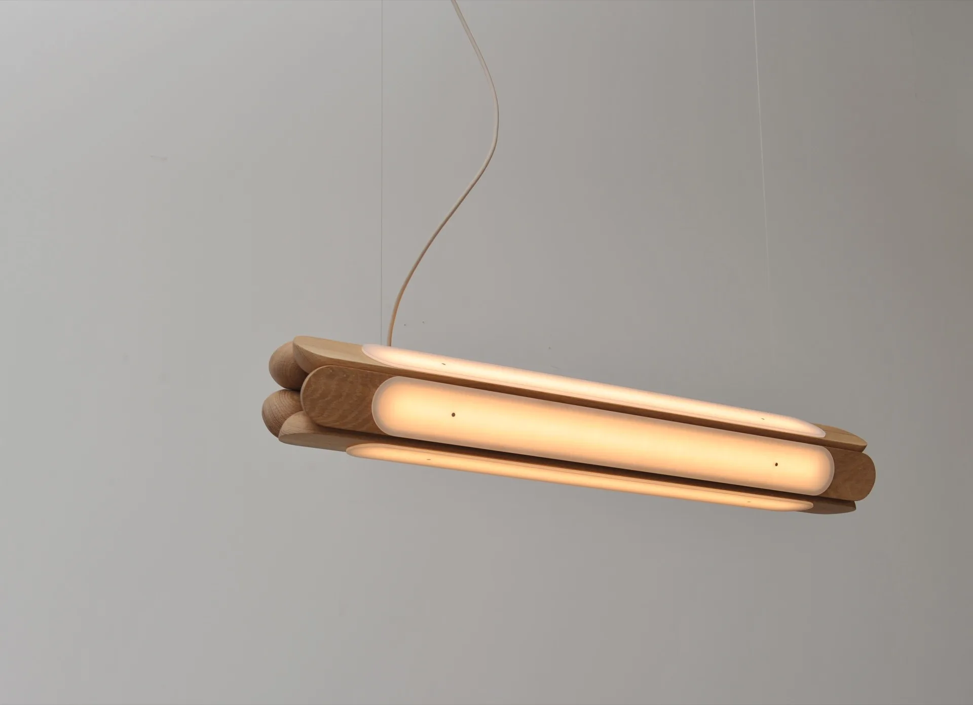 Modern wooden pendant light fixture with LED strip against a plain white wall.
