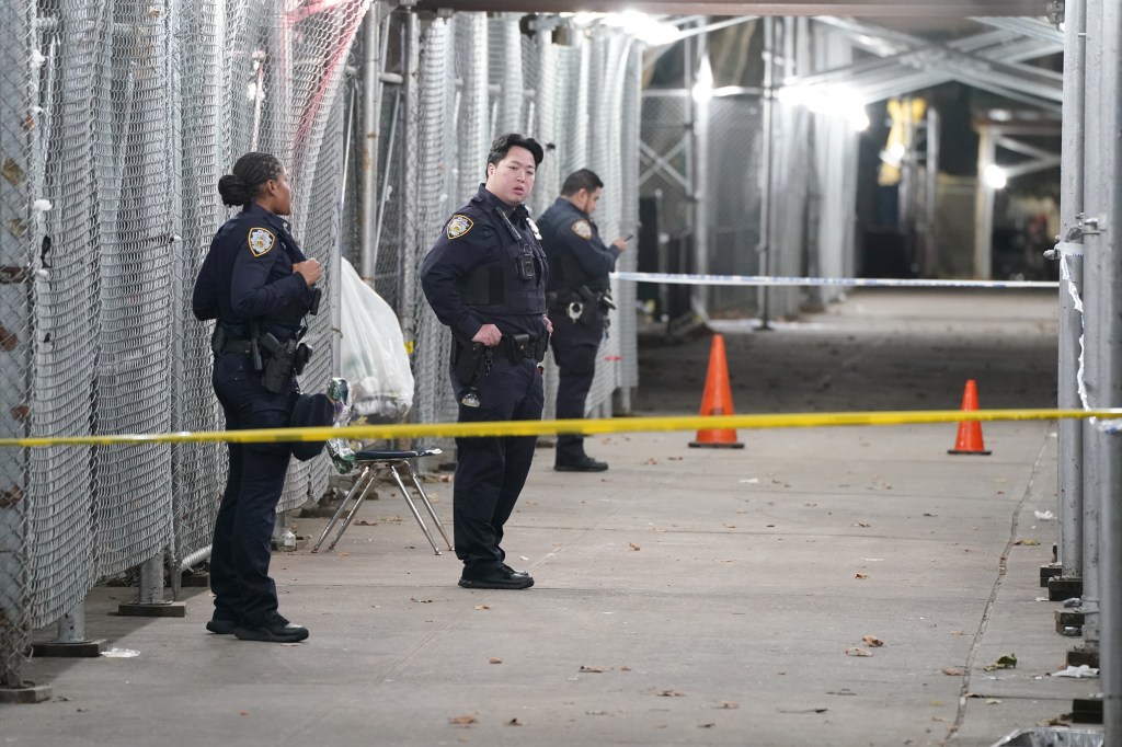 Police officers gather at a shooting scene behind yellow police tape in New York.