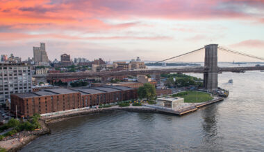Aerial view of the Brooklyn Bridge, Brooklyn Bridge Park, and the East River at sunset.