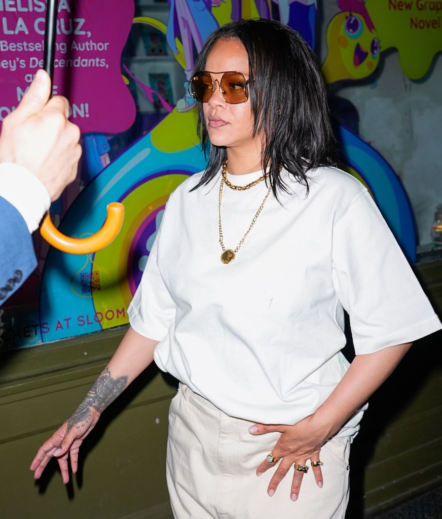 Rihanna wearing a white t-shirt, gold chains, and sunglasses while walking in New York City.