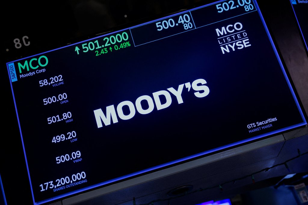 A screen on the New York Stock Exchange trading floor displays the Moody's logo and stock information.