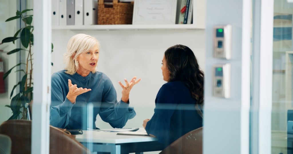 A female manager having a serious discussion with an employee in an office meeting.