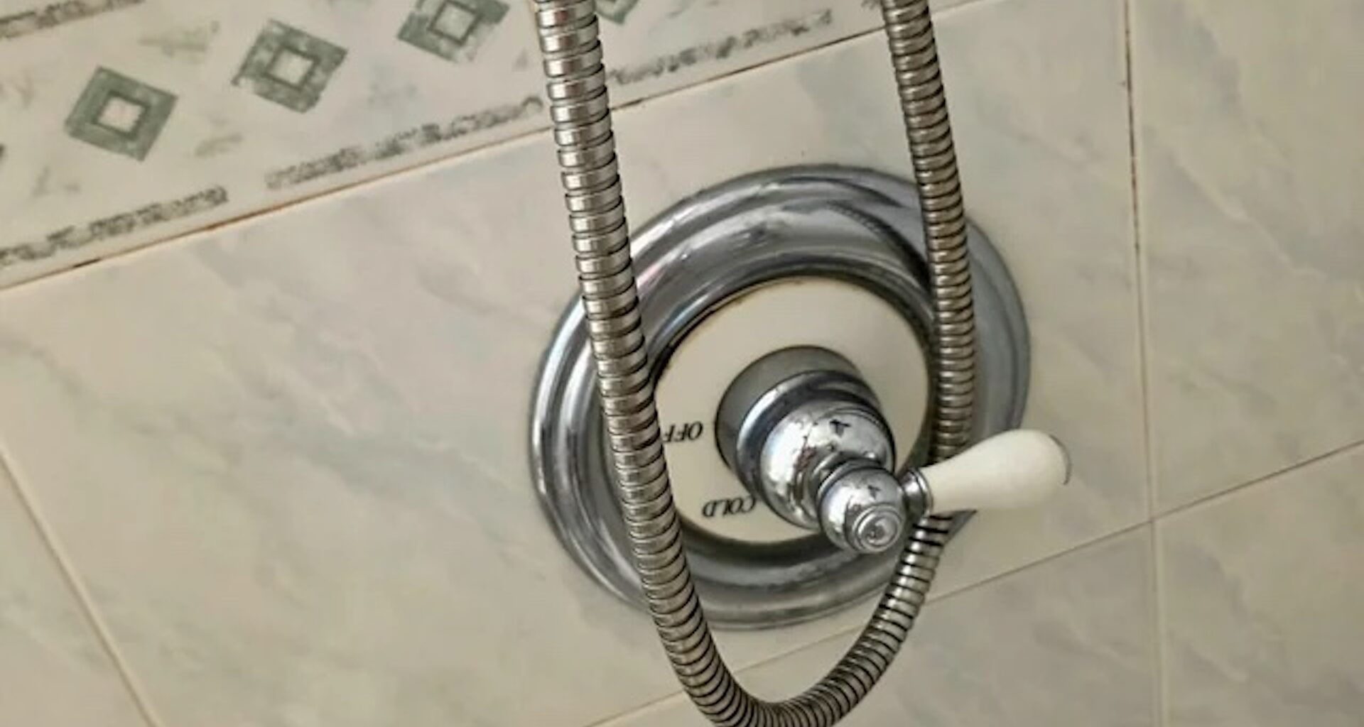 A shower control panel with a chrome handle and a flexible shower hose.