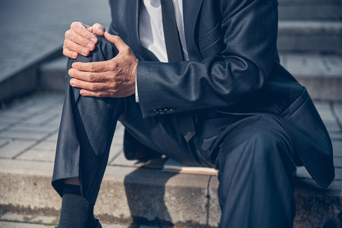 shutterstock_man sitting on steps injured knee