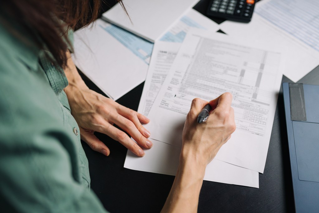 A woman fills out a U.S. tax form 1040.