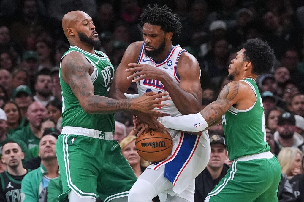 Philadelphia 76ers center Joel Embiid, center, loses control of the ball while trapped by Boston Celtics forward Xavier Tillman, left, guard Anfernee Simons, right, during the first half of an NBA basketball game,