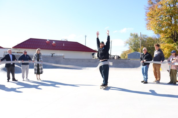Bazaar Skateshop co-owner Tom Hopkins rides through a checkerboard ribbon...