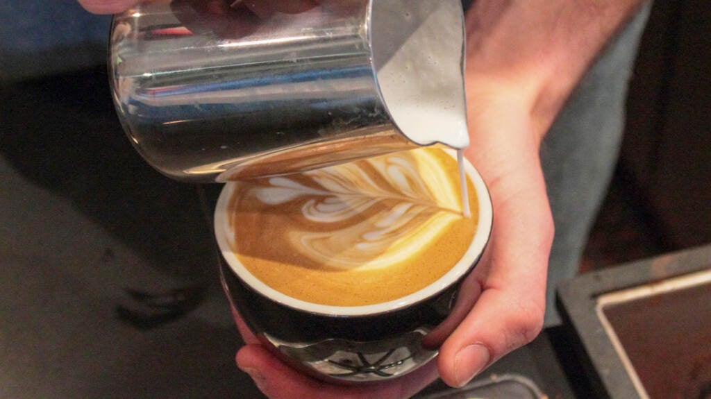 A close-up of a barista making latte art.
