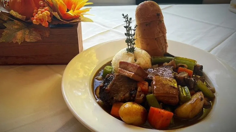 Bowl of stew with potatoes, vegetables, and bread