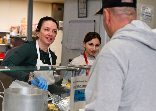 Volunteers Christine Hubany and Lauren Levin, 12, serve food on Thursday, Nov. 27, 2025, during New Bethany's annual free Thanksgiving meal in Bethlehem. (April Gamiz/The Morning Call)