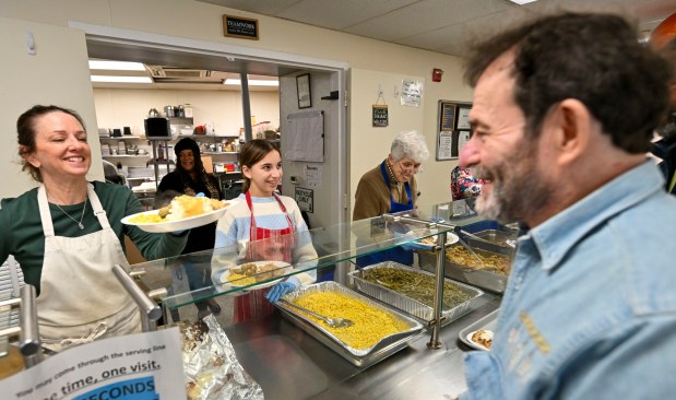 Volunteers Christine Hubany and Lauren Levin, 12, serve Bob Hawk and others on Thursday, Nov. 27, 2025, during New Bethany's annual free Thanksgiving meal in Bethlehem. (April Gamiz/The Morning Call)