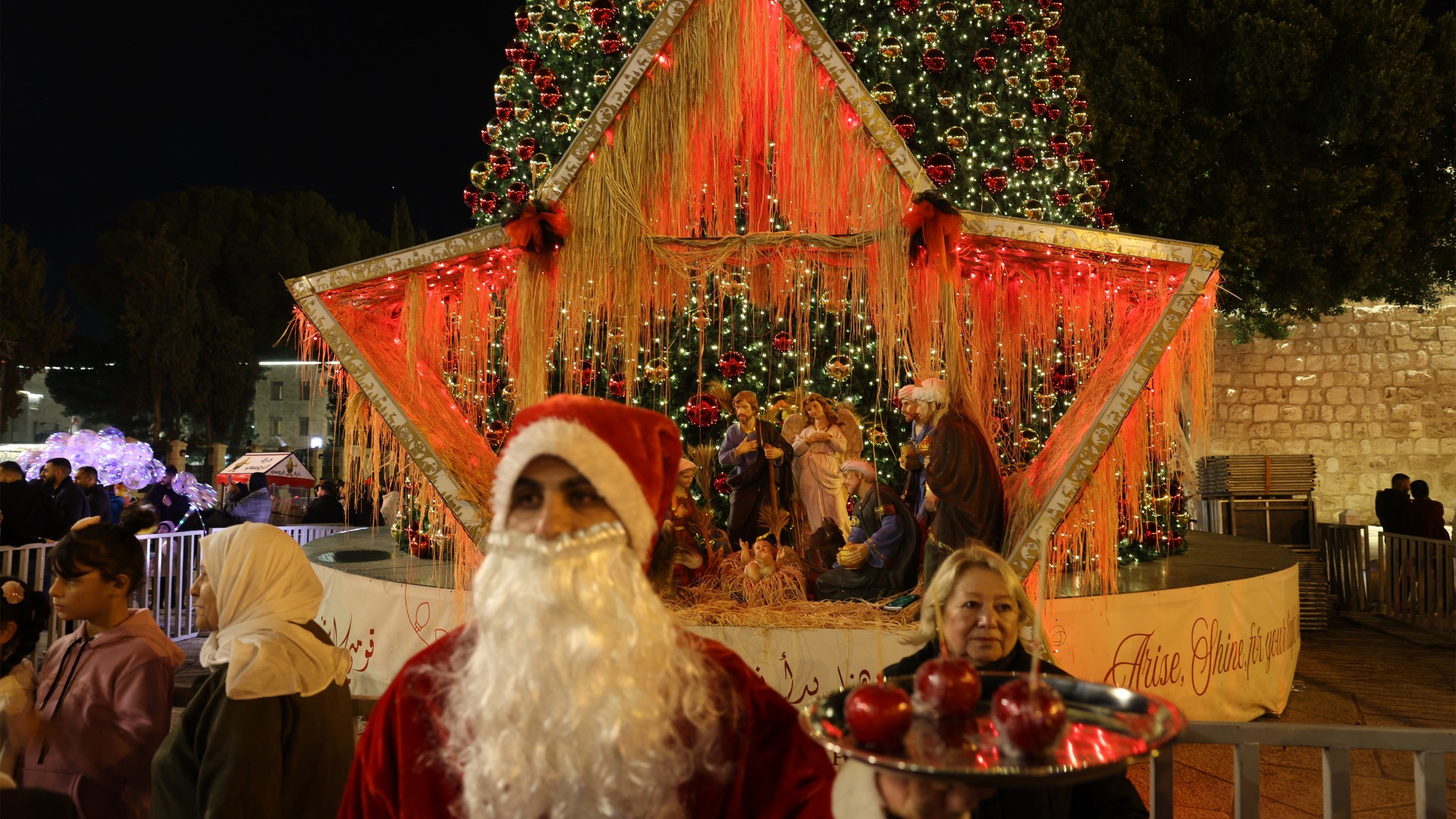 A man dressed as Santa Claus at the Nativity Square with pilgrims and people before midnight mass at the Nativity Church in Bethlehem, in the occupied West Bank