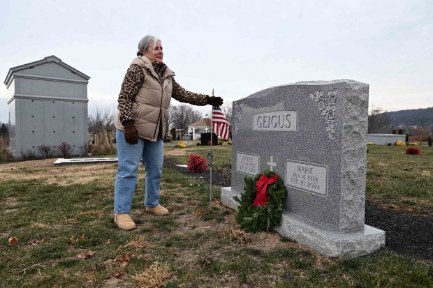 Leeann DeFusco of East Nantmeal Township, Chester County, places a wreath at her father's grave during a Wreaths Across America ceremony at Gethsemane Cemetery in Muhlenberg Township on Saturday, Dec. 13, 2025.   (BILL UHRICH/READING EAGLE)