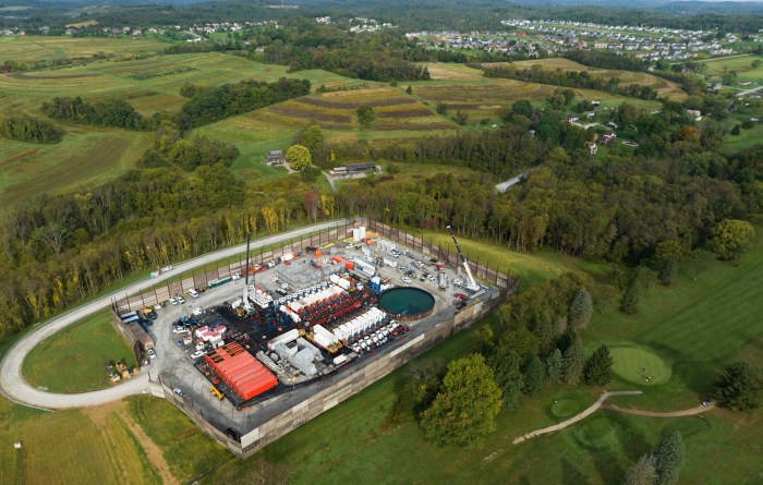 An aerial view of an industrial site amid farm fields and rolling hills.