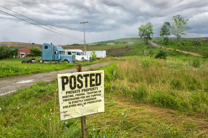 A sign that reads, "Posted Private Property," on a rural road.