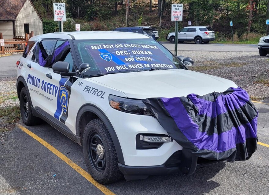 Black and purple bunting, which signifies mourning, hangs from a public safety vehicle in The Hideout. A 26-year-old man with a history of mental health troubles is accused of shooting his parents and killing development security officer Jose Alberto Duran Jr., 55.