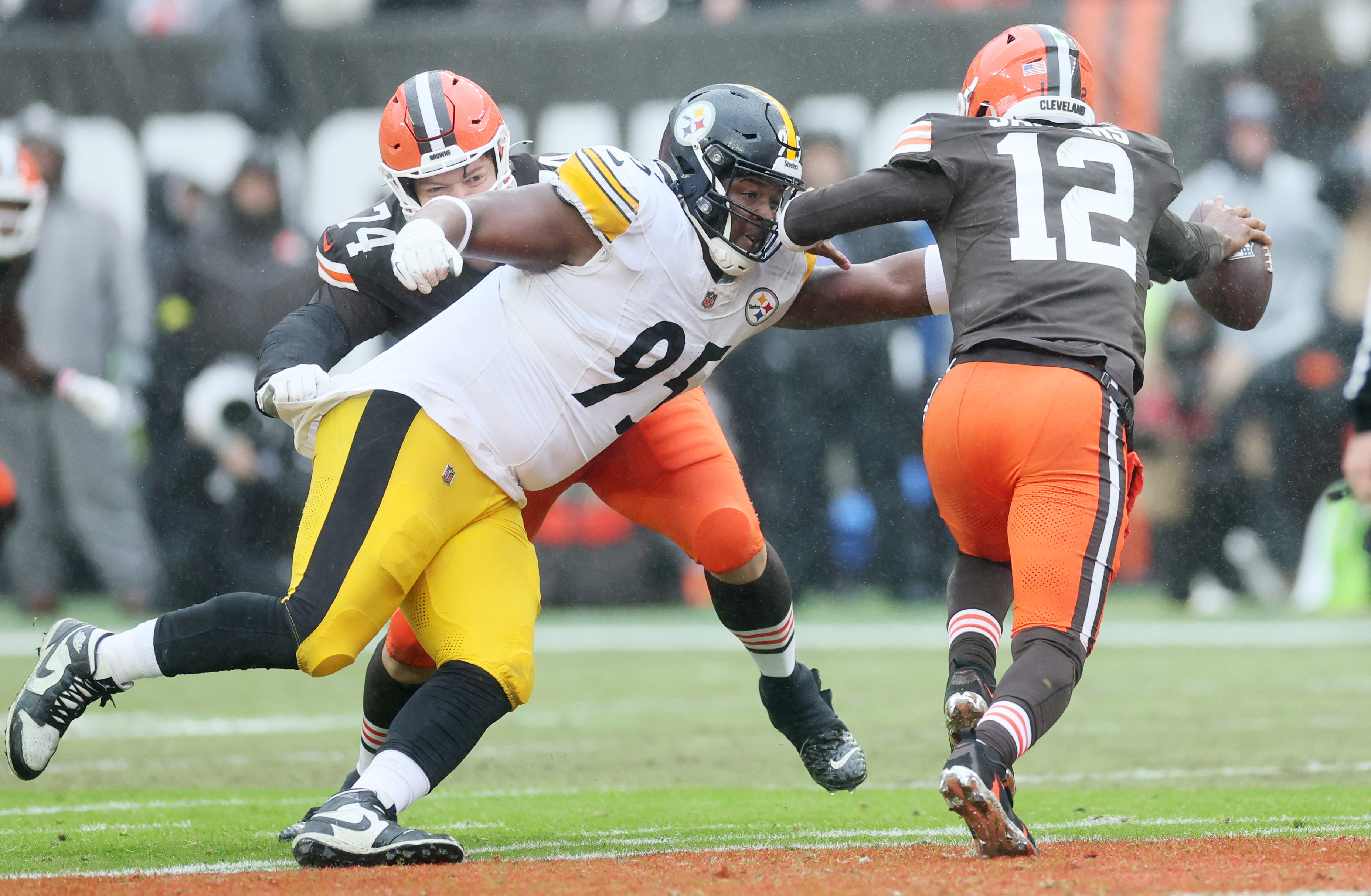 Cleveland Browns quarterback Shedeur Sanders eludes the sack attempt by Pittsburgh Steelers defensive tackle Keeanu Benton on a pass play in the first half. 