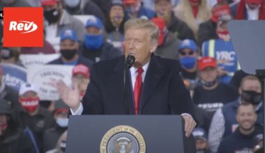Donald Trump stands and speaks at a podium with a crowd behind him. There is a Rev logo in the top left corner.