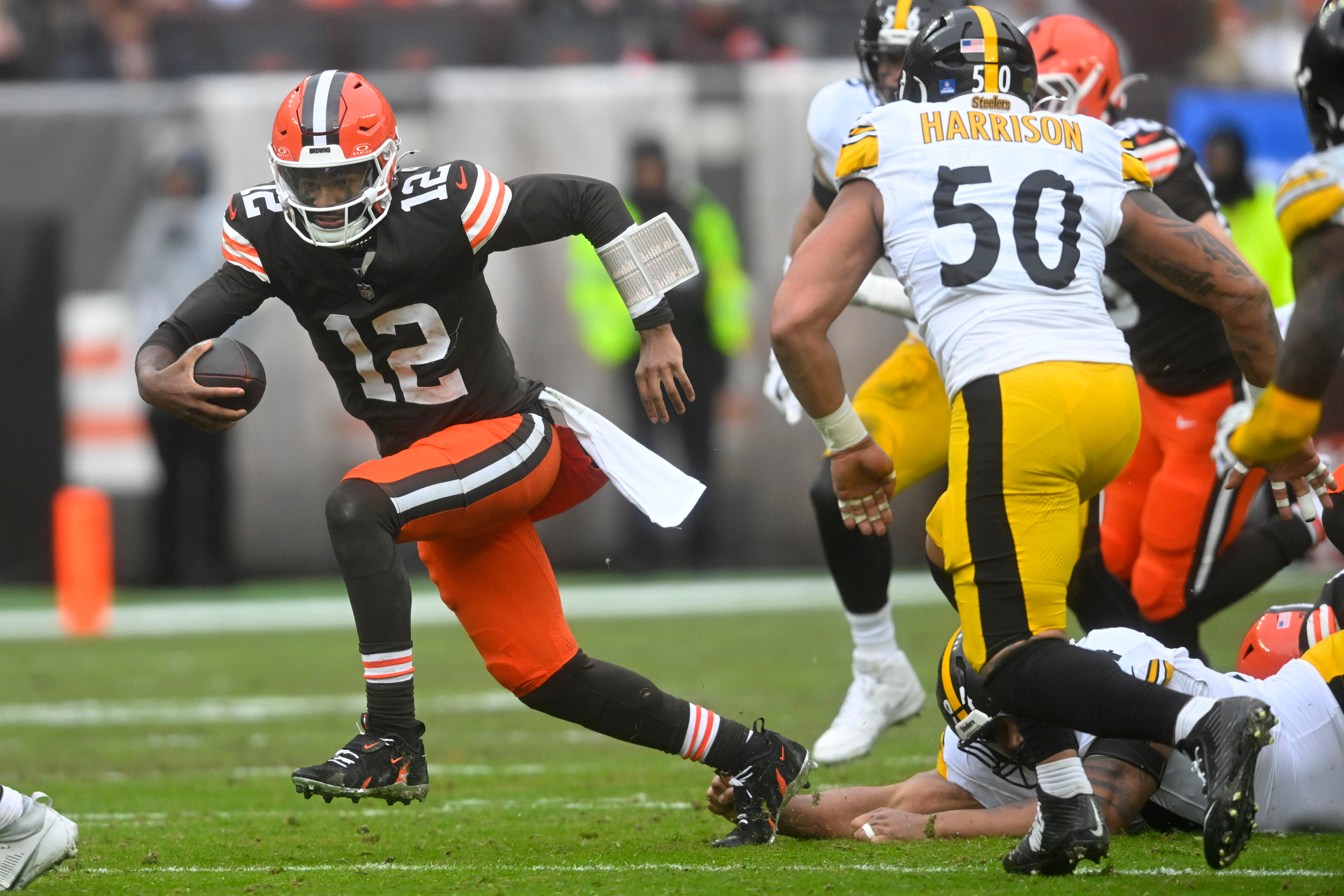 Cleveland Browns quarterback Shedeur Sanders (12) runs from Pittsburgh Steelers linebacker Malik Harrison (50) during the first half of an NFL football game, Sunday, Dec. 28, 2025, in Cleveland. (AP Photo/David Richard)