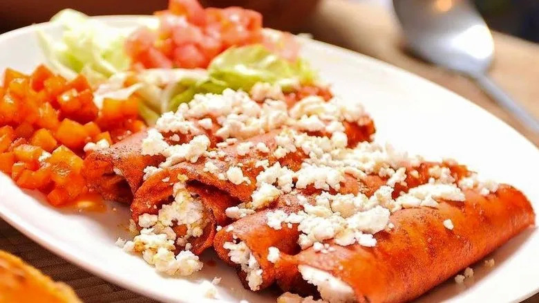 a plate of taquitos covered in cheese