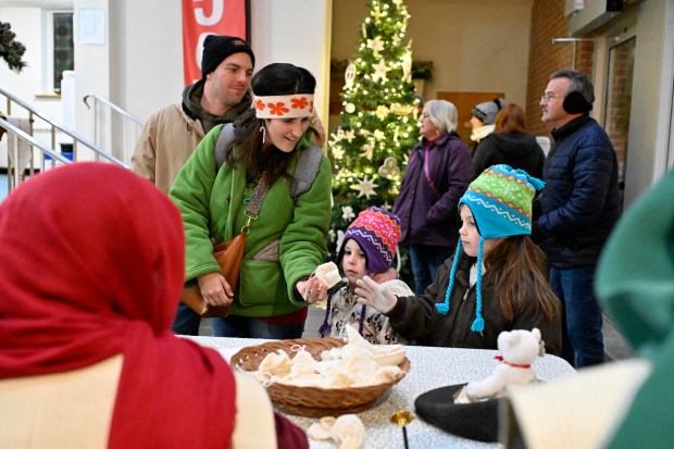 Elizabeth Gordon hands her daughters Abby, 5, and Hannah, 6, a bag of sheckles during "A Night in Bethlehem" at Westminster United Methodist Church. (Thomas Walker/Freelance)