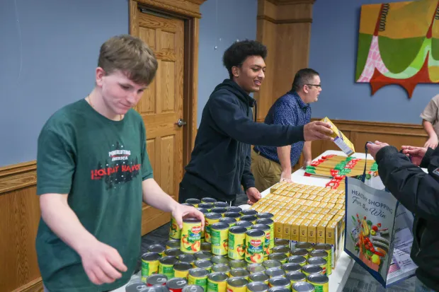 Kayden Bailey, a freshman member of the Pittston Area football team, hands out boxes of pasta during the launch of the Pittston City Food Distribution Pantry at the Pittston Memorial Library on Thursday, Dec. 11, 2025. (JASON ARDAN / STAFF PHOTOGRAPHER)