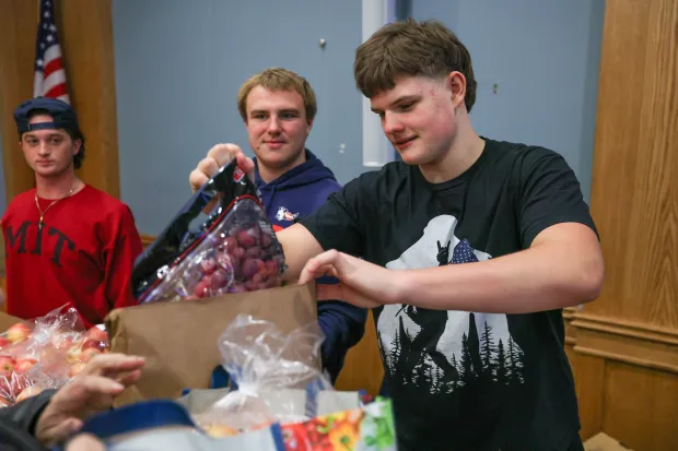 Jimmy Tighe, a junior member of the Pittston Area football team, distrubutes grapes during the launch of the Pittston City Food Distribution Pantry at the Pittston Memorial Library on Thursday, Dec. 11, 2025. (JASON ARDAN / STAFF PHOTOGRAPHER)