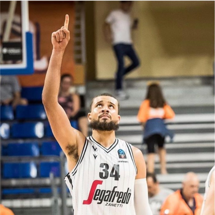 A basketball player points one finger toward the sky