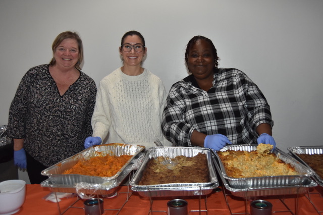 Volunteers help serve food with Miss Ann at the CB...
