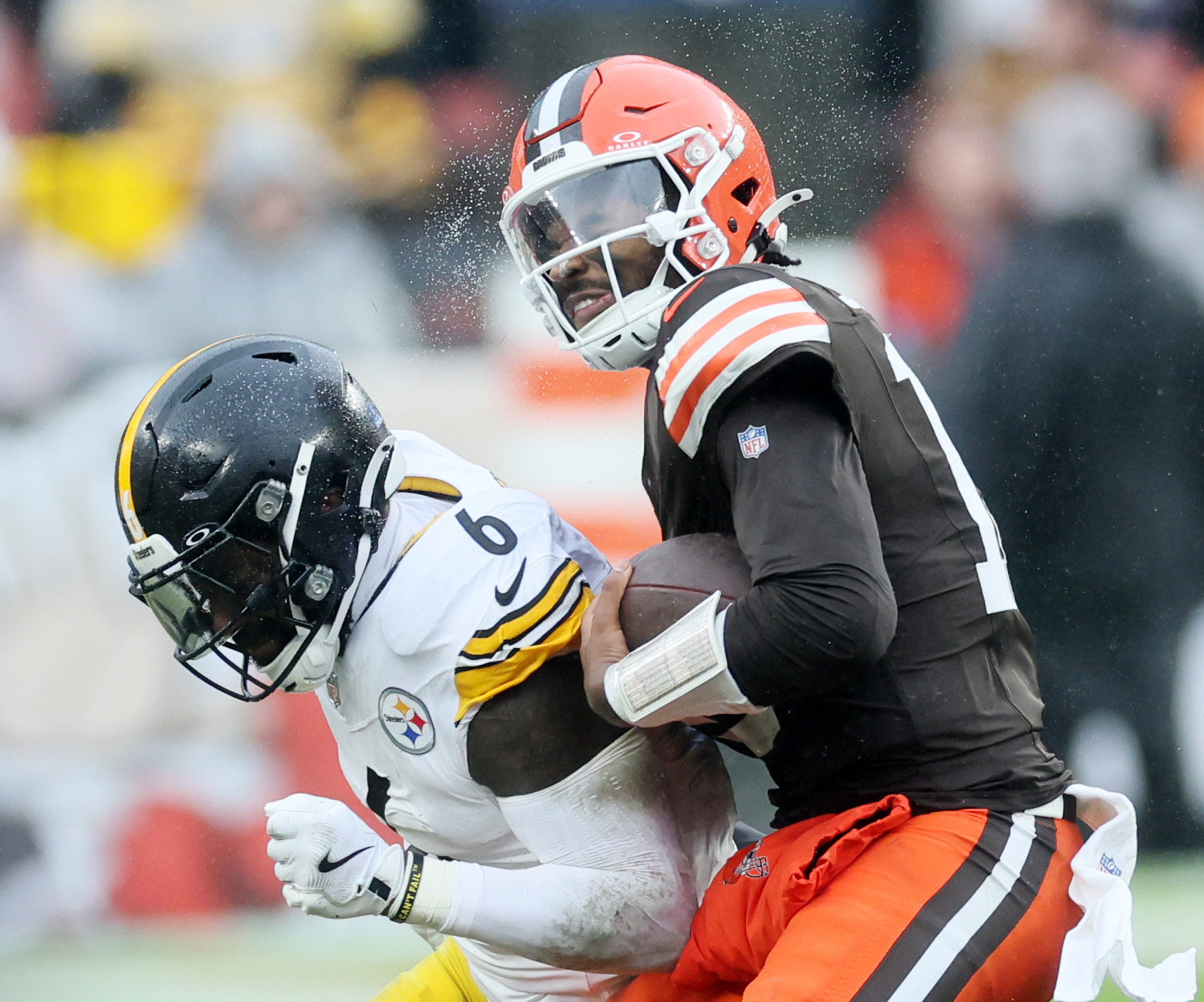 The droplets of rain water on the helmet of Cleveland Browns quarterback Shedeur Sanders sprays off after a hit by Pittsburgh Steelers linebacker Patrick Queen on a keeper in the first half. 
