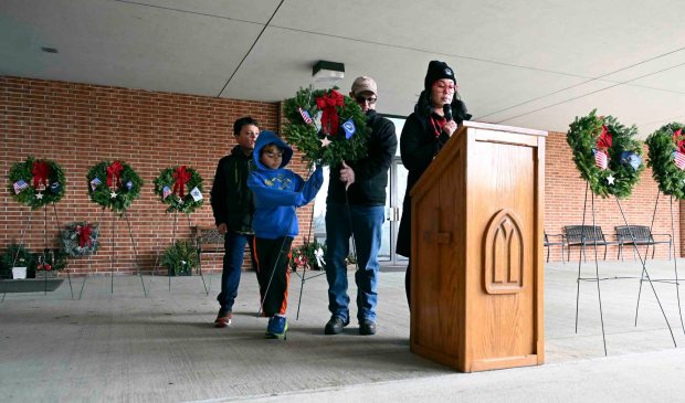 Bryan Gaughan with his sons Devyn, aa, and Elyson, 8, place a wreath honoring Air Force as assistant director Jackie Grauert leads a Wreaths Across America ceremony at Gethsemane Cemetery in Muhlenberg Township on Saturday, Dec. 13, 2025. (BILL UHRICH/READING EAGLE)