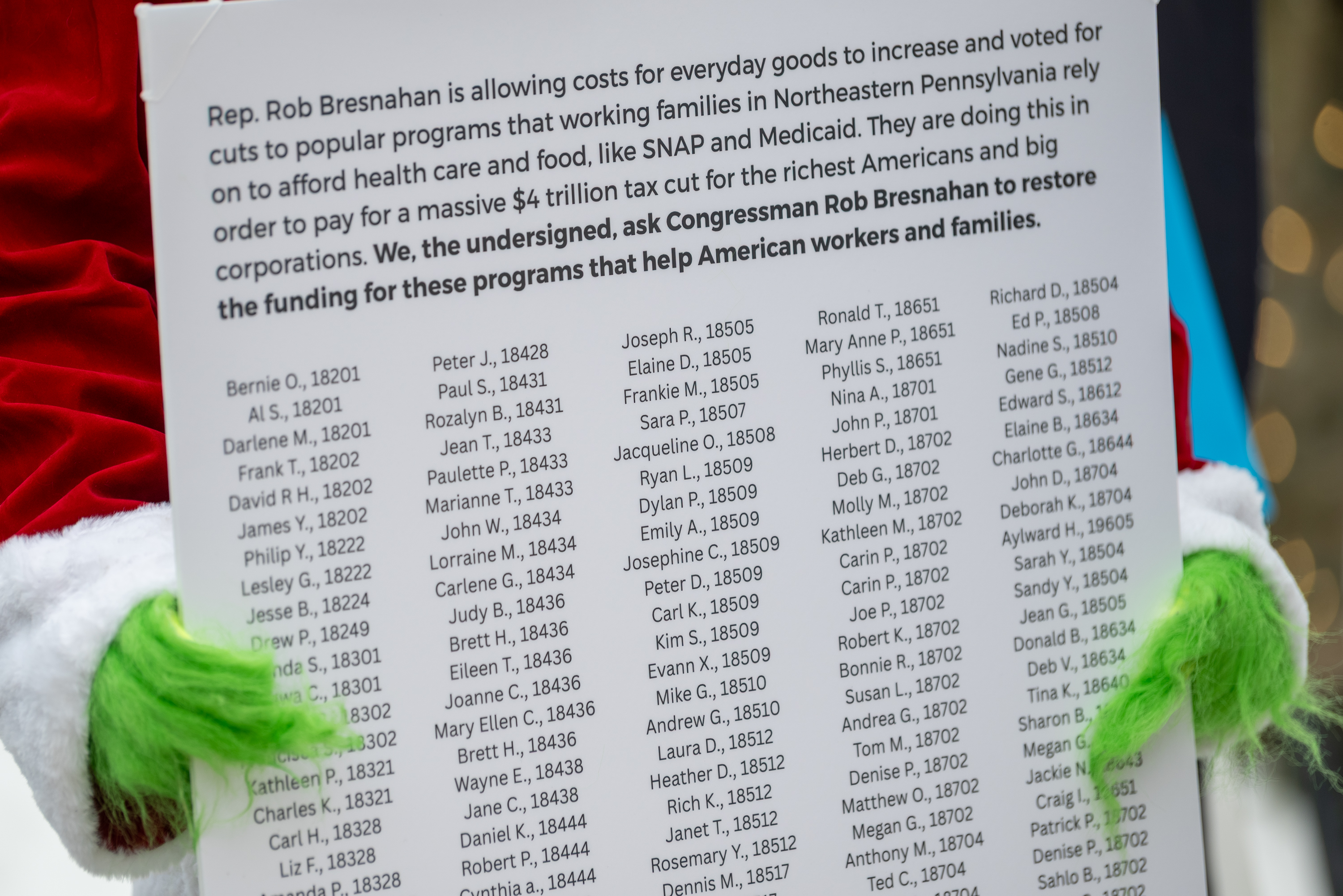 The Grinch holds a poster board version of the petition...