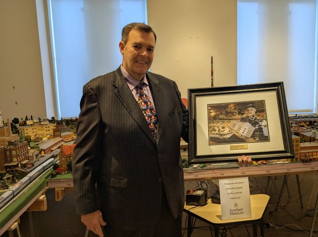 Scranton attorney Chris Munley poses with a portrait of the late Don Clark, creator of the beloved "Miniature Memories" toy train display. Munley bought the long-shuttered collection, which is now on display at the Everhart Museum. (CHRIS KELLY / STAFF PHOTO)