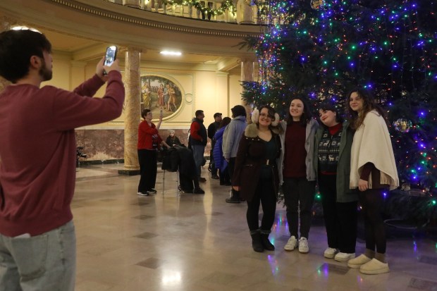 David Devine snaps a photo of his girlfriend Jocelyn Hittle, on the far right, and her friends Sam Magan, Emma Fisher, and Alex Keane during the tree lighting celebration at Marywood University in Dunmore on Wednesday, Dec. 3, 2025. (REBECCA PARTICKA/STAFF PHOTOGRAPHER)