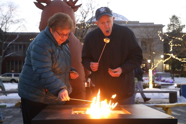 Wayne Puhl blows out his marshmallow while making smores with his wife Jean Puhl during the tree lighting celebration at Marywood University in Dunmore on Wednesday, Dec. 3, 2025. (REBECCA PARTICKA/STAFF PHOTOGRAPHER)