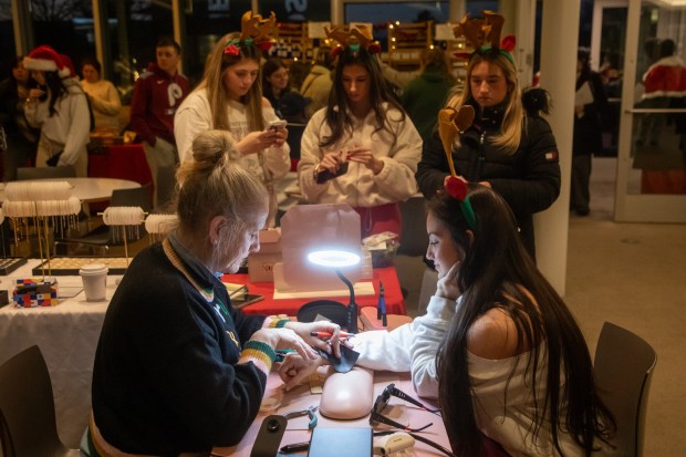 Student Angelina Lee gets piece of permanent jewelry during the tree lighting celebration at Marywood University in Dunmore on Wednesday, Dec. 3, 2025. (REBECCA PARTICKA/STAFF PHOTOGRAPHER)