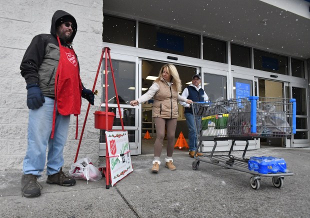 Volunteer for the Salvation Army David Yoder rings his bell as Lori Gergats, of Dickson City, gives him change outside of Walmart in Dickson City Thursday, December 4, 2025. (SEAN MCKEAG / STAFF PHOTOGRAPHER)