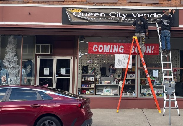 A sign for Queen City Vendors being installed on the building at 210 Lackawanna Ave. in Olyphant. The new business opened Nov. 15. (ROBERT TOMKAVAGE/STAFF PHOTO)