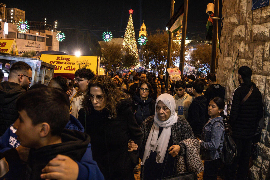 People walk through Nativity Square during a Christmas tree lighting ceremony in Bethlehem, West Bank, on December 6, 2025 