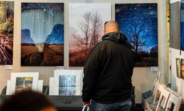 People look to buy fine art photography prints by local artist Scott Krycia inside the Handwerk Haus on Saturday, Dec. 20, 2025, during Christkindlmarkt in Bethlehem. The German-inspired holiday market, which closes Sunday, Dec. 21, 2025, features artisan vendors, festive treats and family activities. (April Gamiz/The Morning Call)