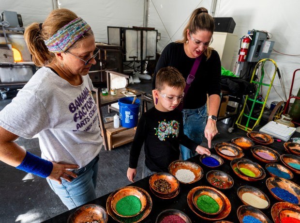 Instructor Heidi Wrobel helps Joey Sulovisk, 7, and his mother, Lauren Sulovski, pick out colors for his glass ornament made from molten glass Saturday, Dec. 20, 2025, during Hot Glass Experience at Christkindlmarkt in Bethlehem. The German-inspired holiday market, which closes Sunday, Dec. 21, 2025, features artisan vendors, festive treats and family activities. (April Gamiz/The Morning Call)