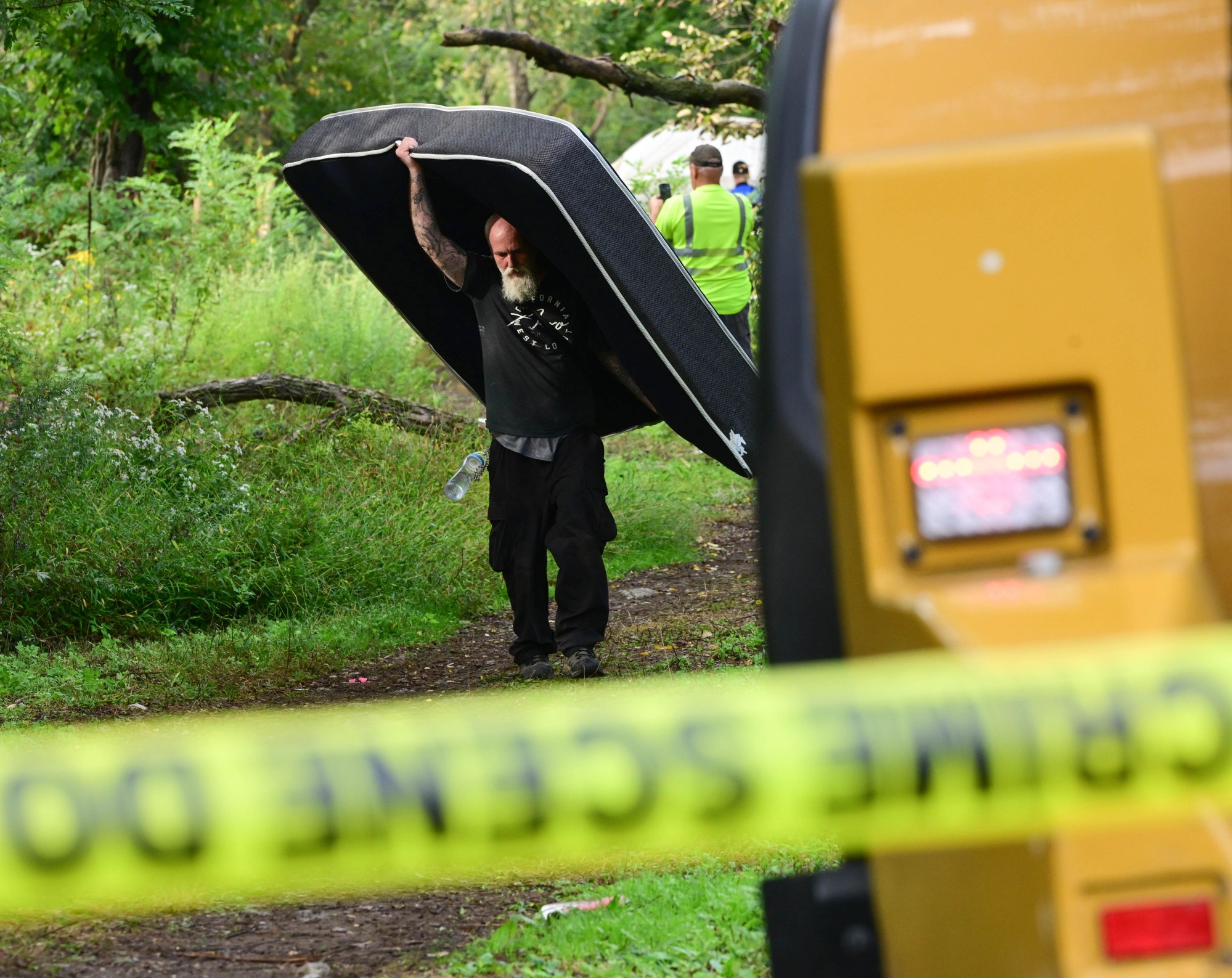 Michael Wilson carries a mattress Monday, Sept. 29, 2025, at the Jordan Creek homeless encampment in Allentown during a sweep by city officials to clear residents out of the site. Allentown officials announced in early August that the camp would be cleared, citing flooding concerns. After an initial deadline of Aug. 25, Allentown Mayor Matt Tuerk extended the evacuation date to Monday to coincide with the opening of the Allentown YMCA's warming station. Despite the advance warning, however, some of the residents stayed up until the last possible moment, saying they had nowhere else to go. Wilson lives in a nearby encampment. (Monica Cabrera/The Morning Call)