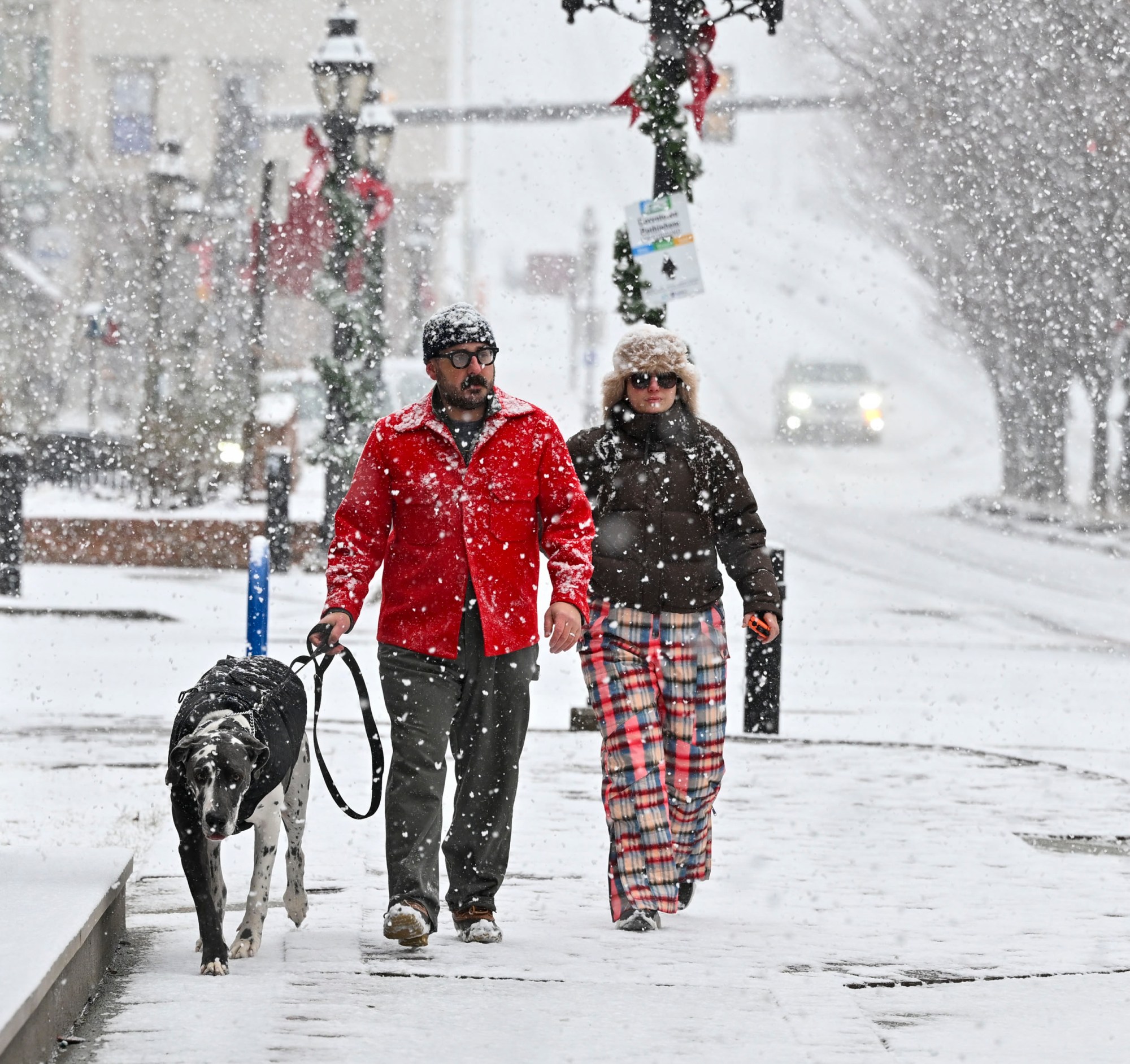 Zach Martin and Duygu Allan of Bethlehem walk through heavy snow with Boyd, a great Dane who loves the snow, Sunday, Jan. 19, 2025, in Bethlehem. (April Gamiz/The Morning Call)