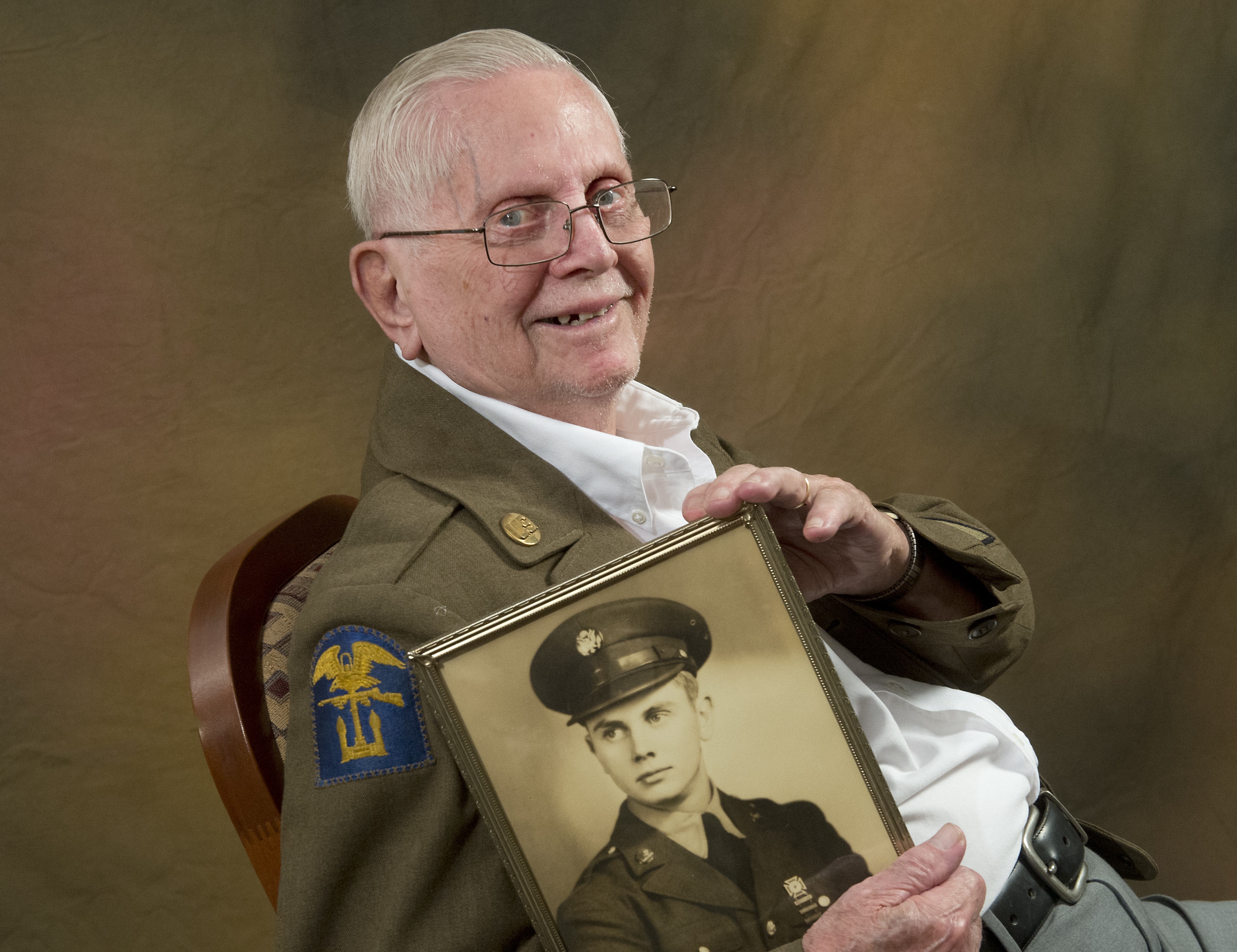 Dick Schermerhorn, 91, hold a portrait taken at Fort Leonard...