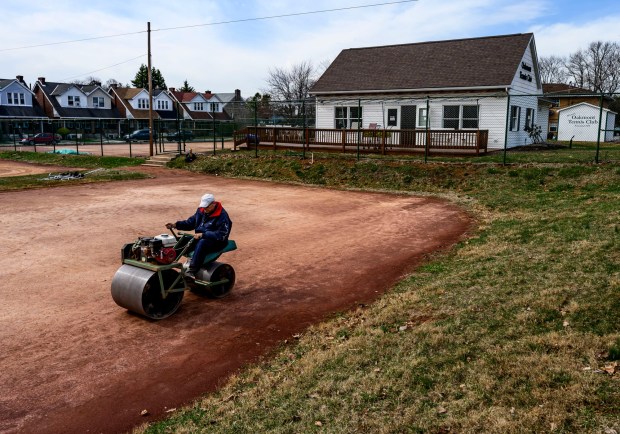 Dave Bobb of Allentown uses a roller to smooth the red clay on a tennis court Wednesday, March, 19, 2025, at Oakmont Tennis Club in Allentown. Founded in 1919, the tennis club has the only clay tennis courts in Eastern Pennsylvania. (April Gamiz/The Morning Call)
