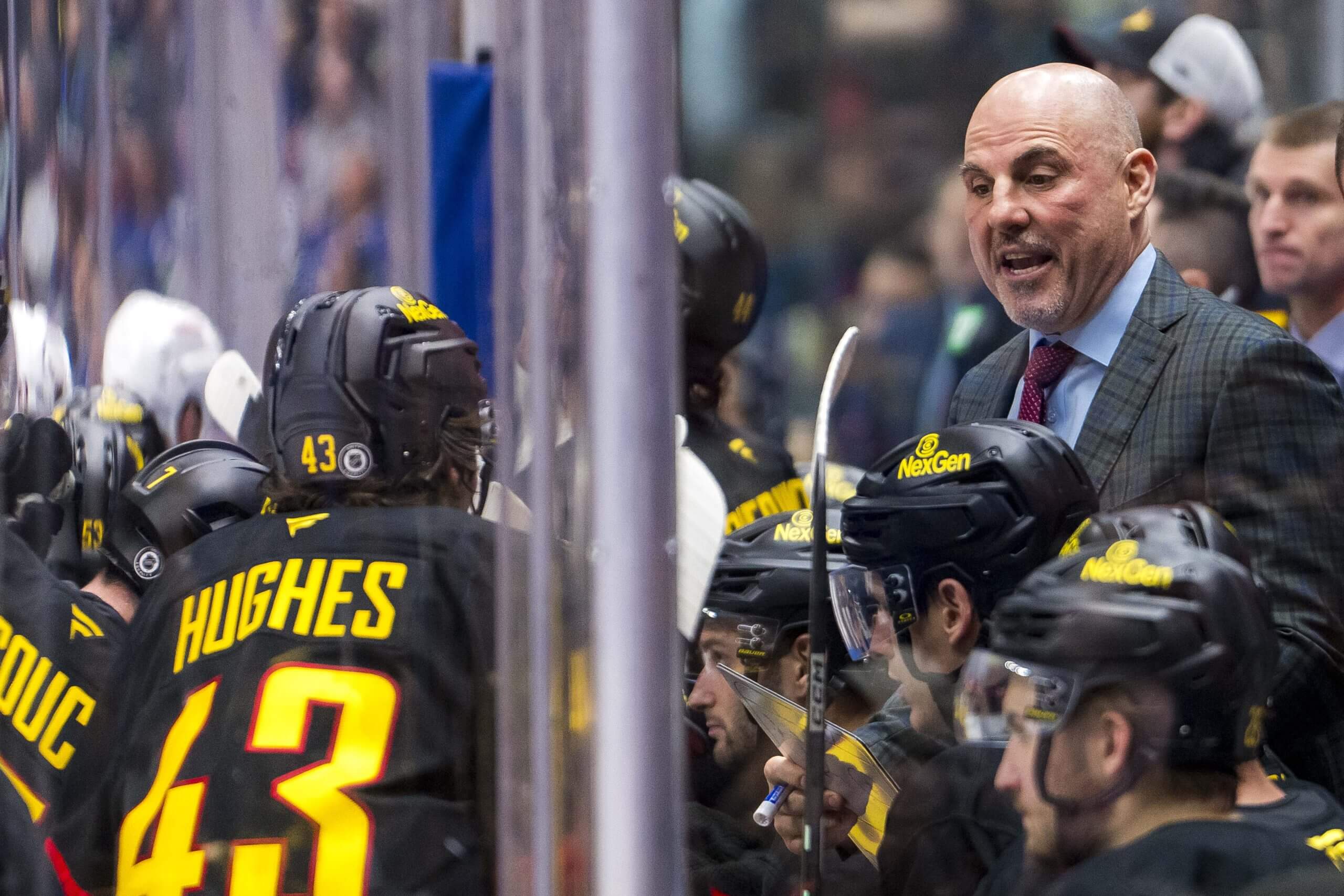 Rick Tocchet, in suit, speaks to Quinn Hughes, No. 43, when he coached the Canucks.